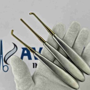 Gloved hand holding 3 Warwick James dental root elevators showing gold titanium working tips and ergonomic handles.