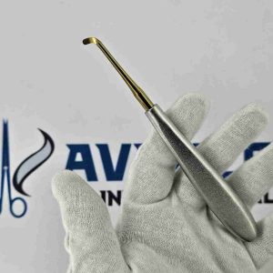 Right angled Warwick James dental elevator with gold titanium tip held in a gloved hand for tooth extraction.