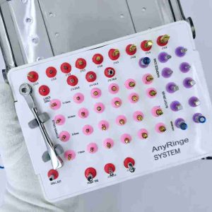 Gloved hand holding an open AnyRinge System dental implant drill kit tray.