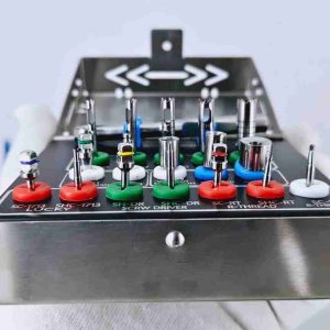 Close-up of dental implant removal instruments organized in color-coded silicone grommets on a metal tray.