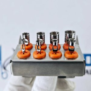 Side profile of surgical dental trephine drill bits measuring 3mm to 6mm mounted on a metal sterilizing rack.
