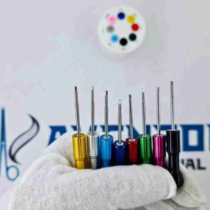Hand holding color-coded dental implant drivers for surgical restoration.